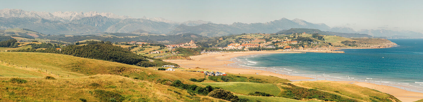 Die ruhige Küste von Kantabrien fließt nahtlos in das grüne und majestätische Bergpanorama, das bezaubernd in der Ferne liegt.
