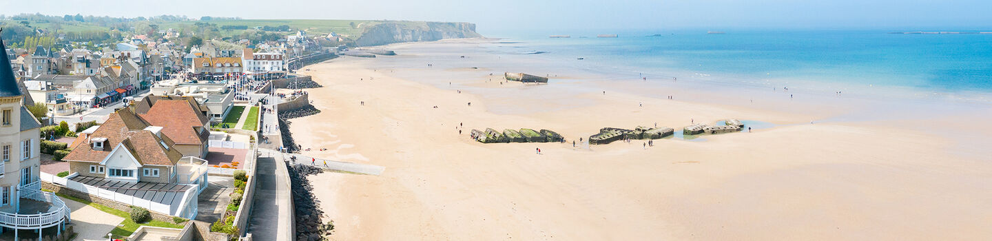 Panoramablick auf Arromanches in der Normandie mit den Überresten des Mulberry-Hafens und der Küste im Hintergrund