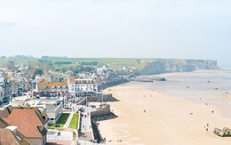 Blick auf Arromanches in der Normandie (Frankreich), mit der Küste im Hintergrund