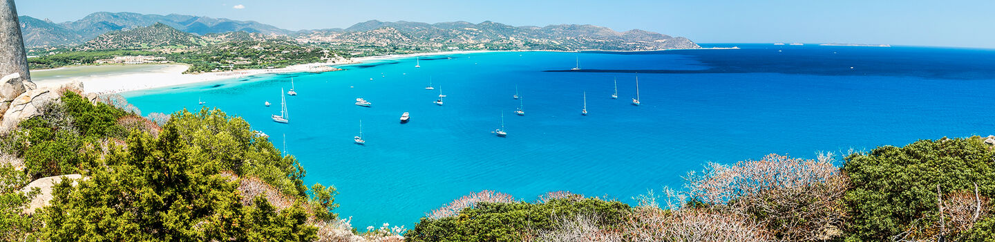Ein idyllischer Blick auf den Strand von Porto Giunco auf Sardinien, mit seinem feinen weißen Sand und dem kristallklaren, türkisfarbenen Wasser.