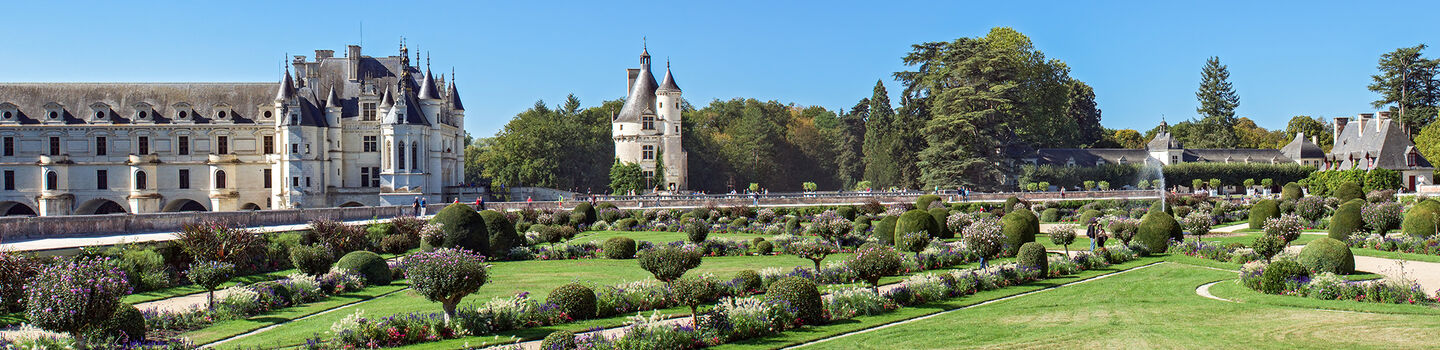 Panoramablick auf das Château de Chenonceau (Frankreich) mit seinen Bögen über dem Fluss Cher und den gepflegten Gärten