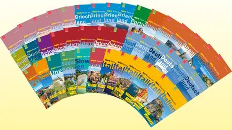 Eine fächerförmige Anordnung farbenfroher Reiseführer vor leuchtend gelbem Hintergrund. Jedes Cover zeigt Ländernamen und lebendige Landschaftsbilder.