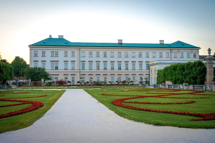 Das Schloss Mirabell in Salzburg mit Garten und Blumenbeeten im Vordergrund.