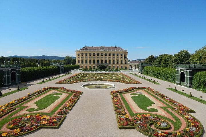 Das Schloss Schönbrunn in Wien mit seinen prächtigen barocken Fassaden und den weitläufigen, gepflegten Gärten im Vordergrund.