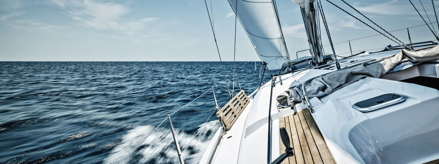 Ein Segelboot fährt auf offener See bei klarem Himmel.