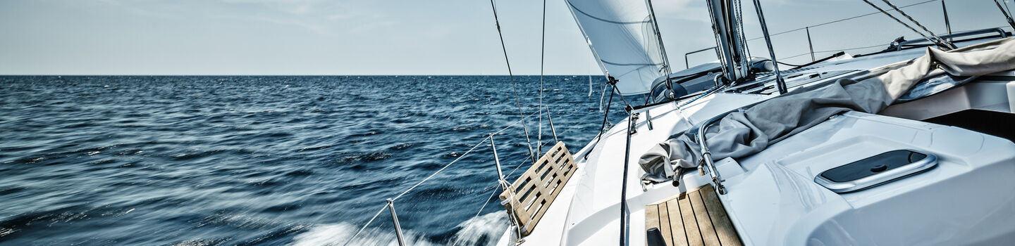 Ein Segelboot fährt auf offener See bei klarem Himmel.