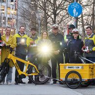 Die Verantwortlichen der Radlichtaktion haben sich alle für ein Gruppenfoto versammelt und leuchten mit einem vorschriftsgemäßen Radlicht in die Kamera