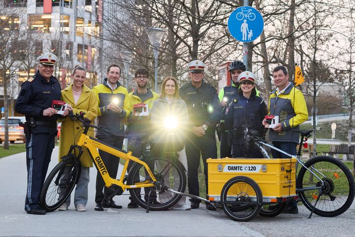 Die Verantwortlichen der Radlichtaktion haben sich alle für ein Gruppenfoto versammelt und leuchten mit einem vorschriftsgemäßen Radlicht in die Kamera