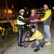 Gemeinsam mit der Polizei informieren ÖAMTC-Techniker eine Radfahrerin mit Infomaterial und tauschen ihr Licht aus.