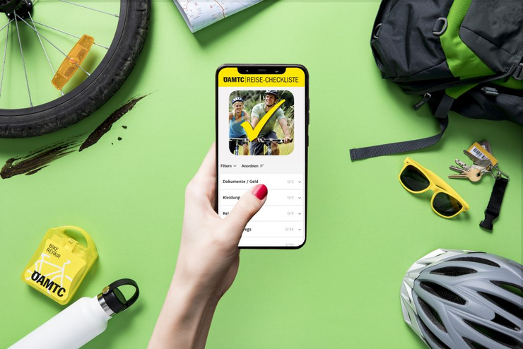 Frau hält Smartphone in Hand, auf dem die ÖAMTC Reise-Checkliste für Radfahren zu sehen ist.
