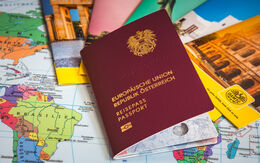 Österreichischer Reisepass, der auf einer Landkarte und Prospekten liegt.