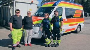 Ein ÖAMTC-Mitglied steht mit Sanitäter:innen vor einem Rettungsfahrzeug.