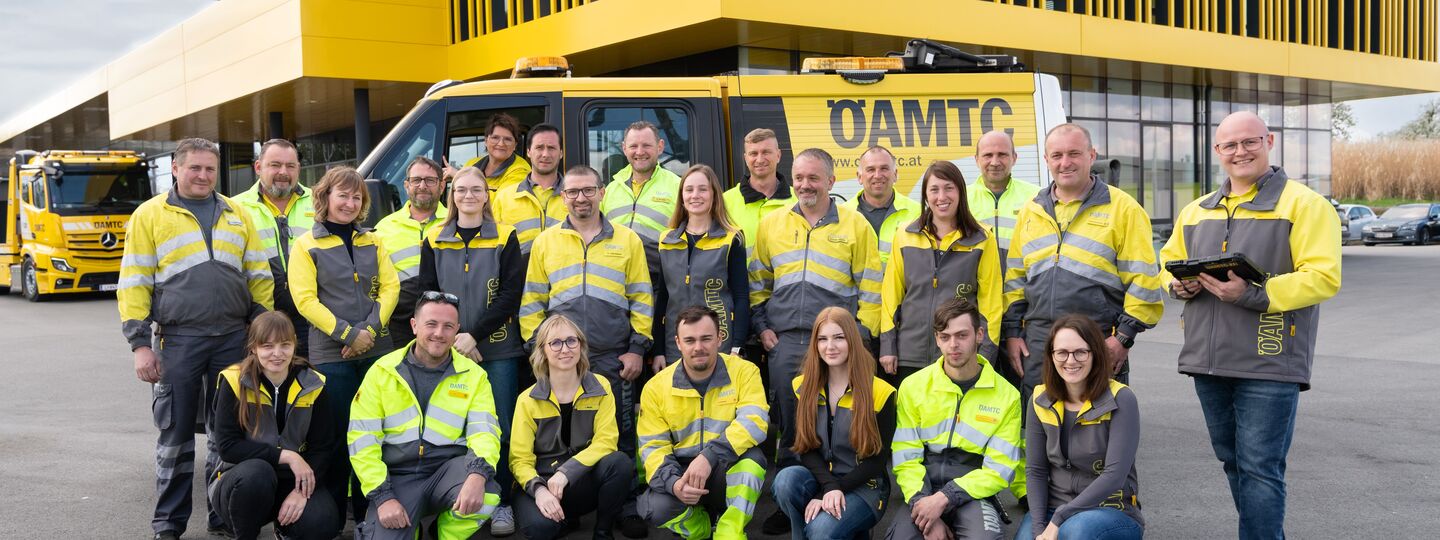 Die Kolleginnen und Kollegen vom Stützpunkt Ried stehen vor einem Pannenfahrzeug und dem Stützpunkt für ein Teamfoto.