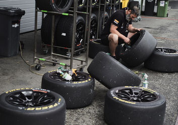 Eine Person sitzt zwischen einzelnen Reifen und putzt die Felge eines solchen.