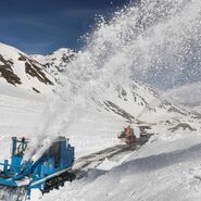 Schneepflug räumt Schnee von einer Straße.