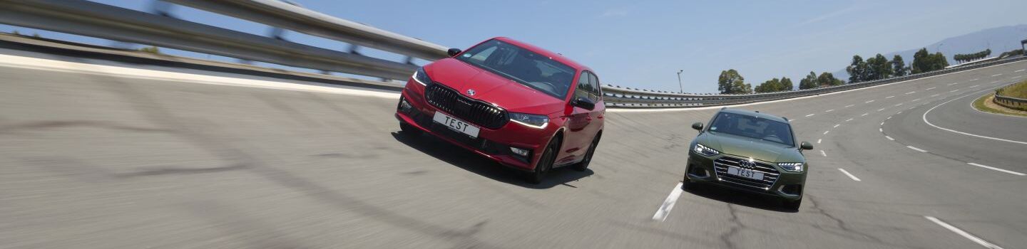 Ein rotes und ein grünes Auto fahren nebeneinander auf einer Teststrecke.