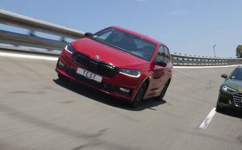 Ein rotes und ein grünes Auto fahren nebeneinander auf einer Teststrecke.