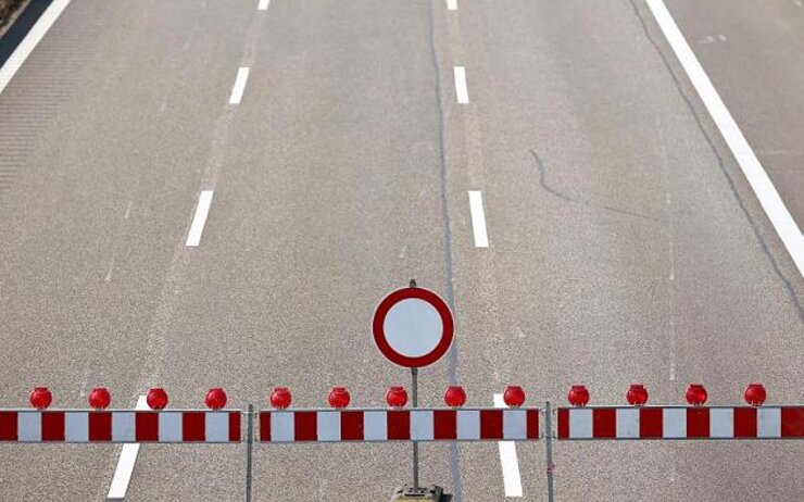 Drei Fahrstreifen einer Autobahn mit einer Absperrung und einem "gesperrt" Verkehrszeichen.