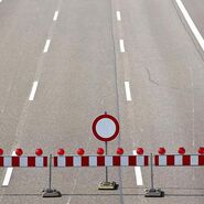Drei Fahrstreifen einer Autobahn mit einer Absperrung und einem "gesperrt" Verkehrszeichen.