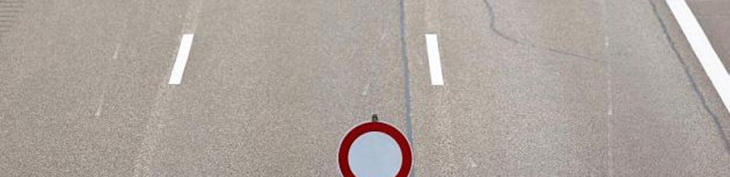 Drei Fahrstreifen einer Autobahn mit einer Absperrung und einem "gesperrt" Verkehrszeichen.