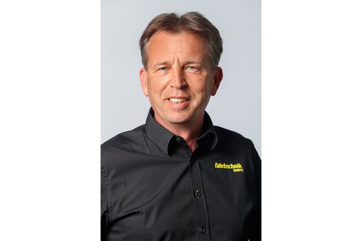 Porträt eines lächelnden Mannes mittleren Alters in einem schwarzen Hemd mit der Aufschrift "ÖAMTC Fahrtechnik"