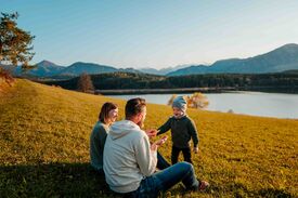 Auf dem Foto ist der Tunersee in herbstlicher Kulisse zu sehen, mit einer Familie mit Kleinkind im Vordergrund.