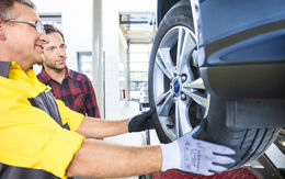 ÖAMTC Techniker und Mitglied begutachten die Profiltiefe eines Autos auf der Hebebühne