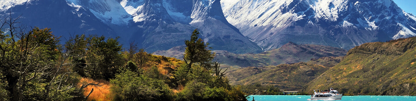 Die Landschaft in Chile offenbart eine raue Schönheit, geprägt von einem stillen See und schneebedeckten Bergen, die eine rustikale und beeindruckende Kulisse schaffen.