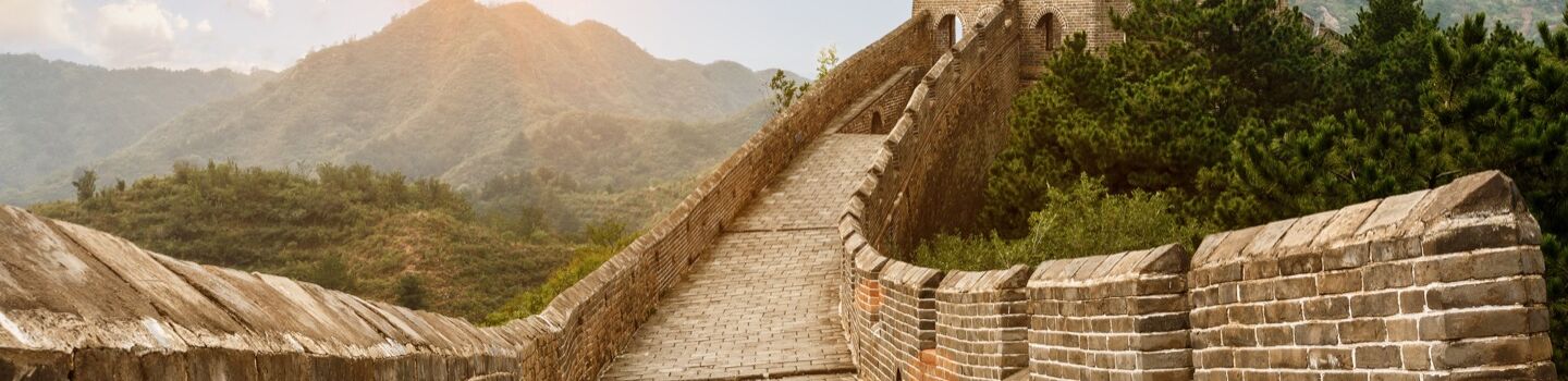 Auf der Chinesischen Mauer, die steil einen bewaldeten Hügel hinauf ansteigt.