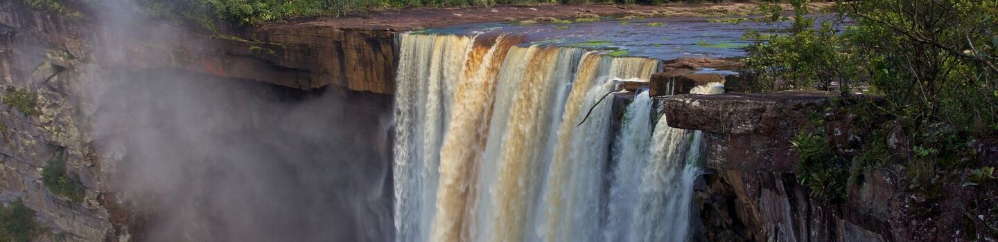 Ein mächtiger Wasserfall stürzt von einer breiten Klippe herab, eine atemberaubende Szenerie der rohen Naturkraft.