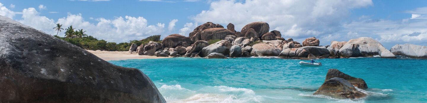 Strandlandschaft auf den Britischen Jungferninseln mit türkisfarbenem Wasser, Felsen und Palmen