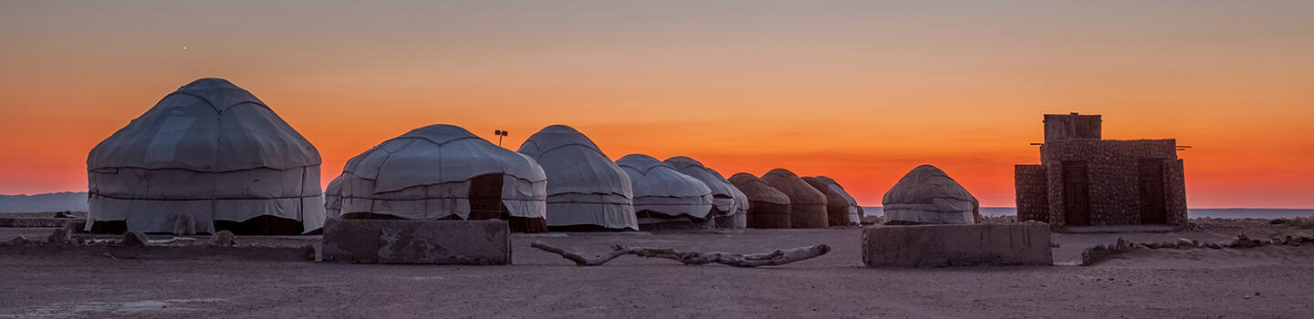 Mehrere Jurten in der Wüste bei Sonnenuntergang