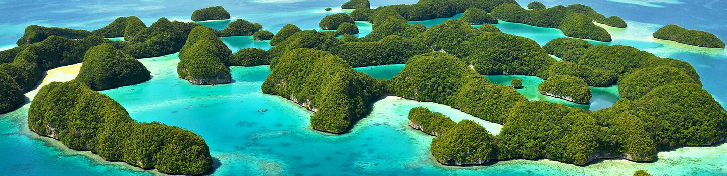 Luftaufnahme der der Chelbacheb-Inseln in Palau: smaragdgrüne Kalksteininseln umgeben von kristallklarem, türkisblauem Wasser.