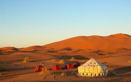 Panoramablick auf traditionelle Wüstenzelte am Rand der Sahara in Marokko, umgeben von endlosen Sanddünen