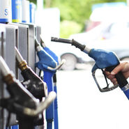Eine Hand nimmt den Tankstutzen in die Hand an einer Tankstelle.