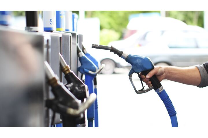 Eine Hand nimmt den Tankstutzen in die Hand an einer Tankstelle.