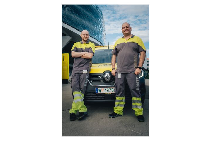 Die beiden Pannenfahrer posieren vor einem Pannenfahrzeug
