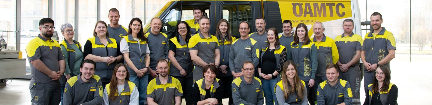 Die Kolleginnen und Kollegen vom Stützpunkt Urfahr stehen vor einem Pannenfahrzeug für ein Teamfoto.