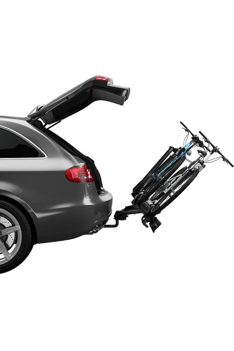 Seitliche Sicht auf ein Auto, dessen Kofferraum geöffnet ist. Auf dem montierten Fahrradträger sind 2 Räder fixiert und der gesamte Träger ist nach hinten gelehnt, damit man ohne Probleme den Kofferraum öffnen und schließen kann.