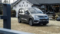 Das Foto zeigt ein stehendes Fahrzeug vor einem Geschäft.