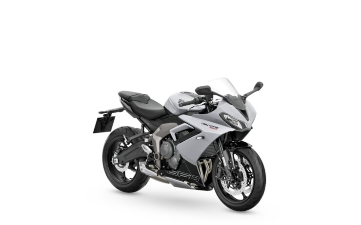 Das Foto zeigt ein stehendes graues Motorrad vor einer weißen Wand.