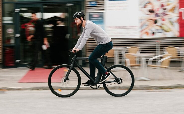 Radfahrer mit Helm fährt auf einem Urban E-Bike.