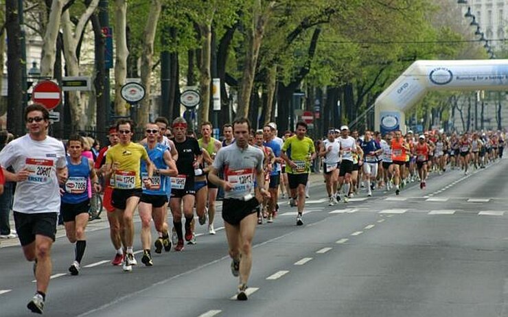 Entlang der Straße laufende Veranstaltungsteilnehmer:innen.