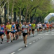 Entlang der Straße laufende Veranstaltungsteilnehmer:innen.