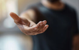 Mann streckt seine offene Hand aus.