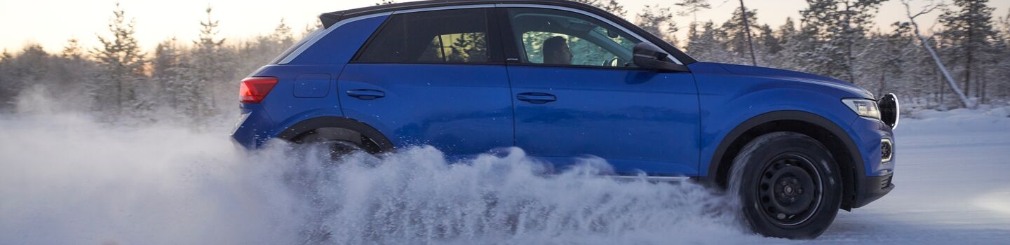 Seitenansicht eines blauen Autos auf einer winterlichen Teststrecke.
