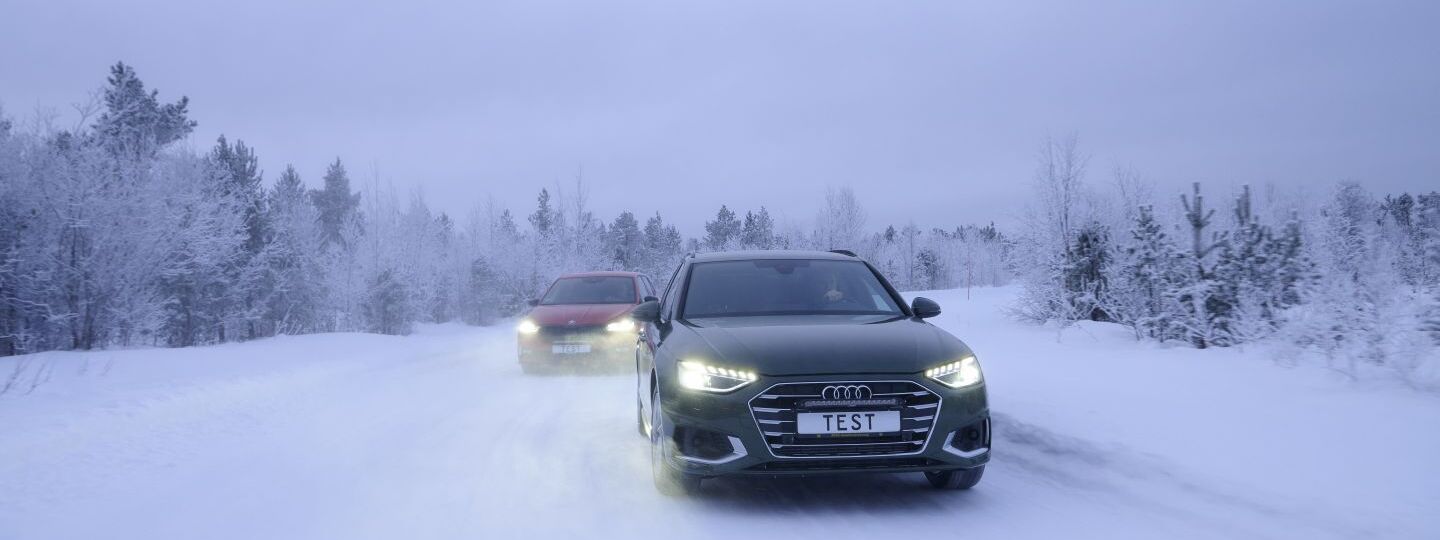 Zwei Autos fahren auf einer Schneefahrbahn. Winterliche und verschneite Bäume und Hintergrund.