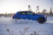 Seitenansicht eines blauen Autos auf einer winterlichen Teststrecke.