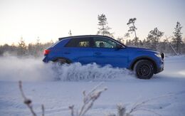 Seitenansicht eines blauen Autos auf einer winterlichen Teststrecke.