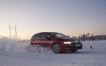 Rotes Auto fährt auf Schneefahrbahn bei Sonnenaufgang